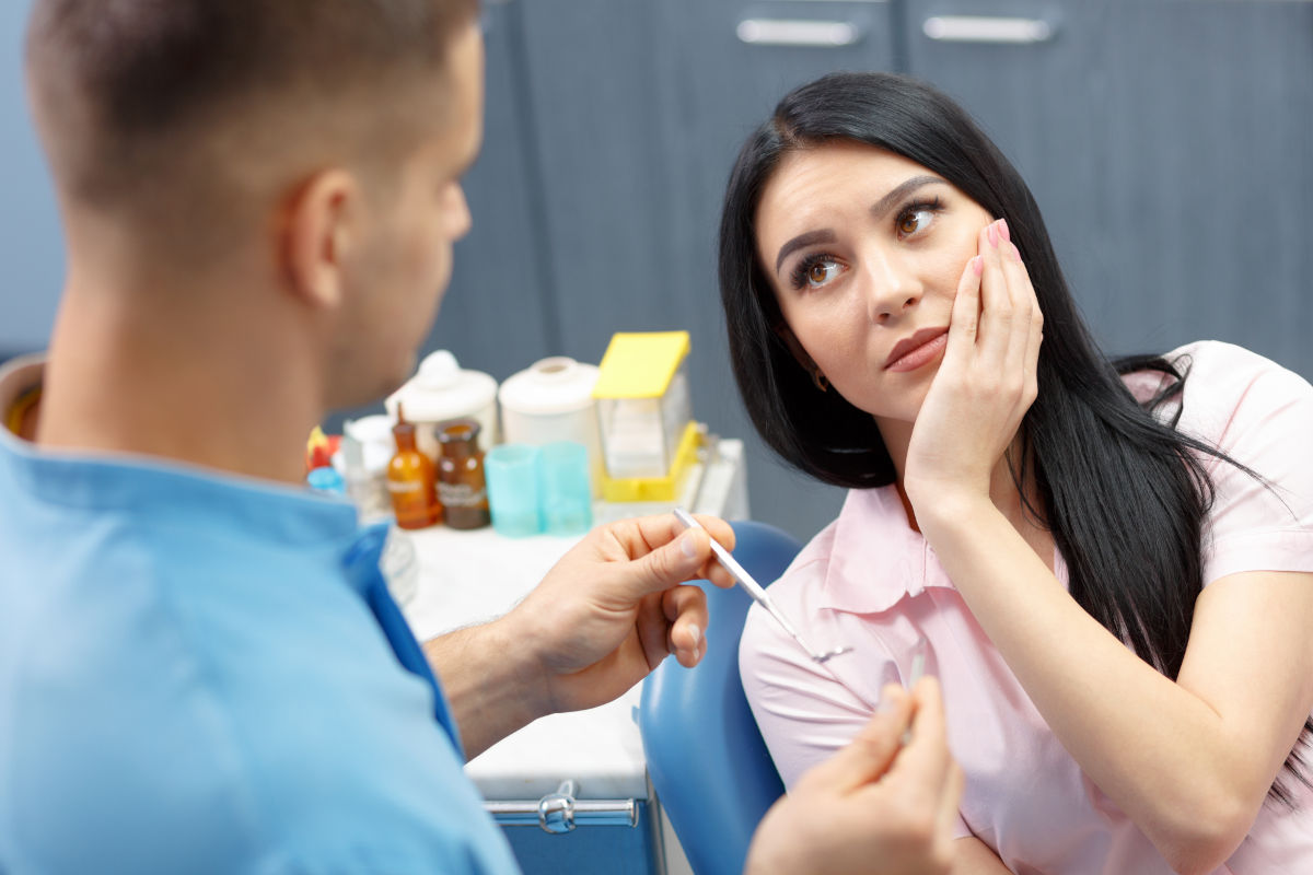 Dentist discussing treatment with a patient holding her cheek