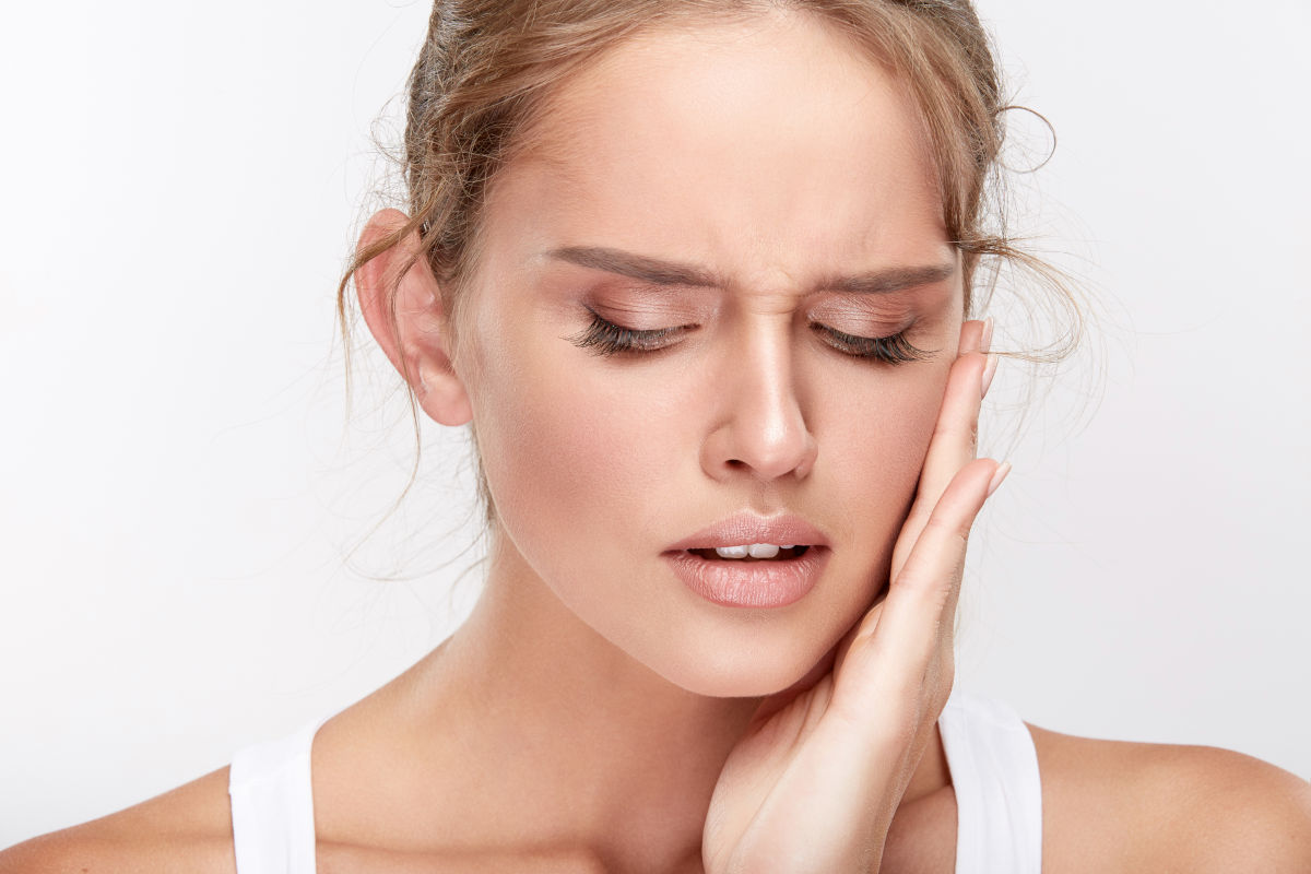 Woman holding her cheek in pain from a persistent toothache