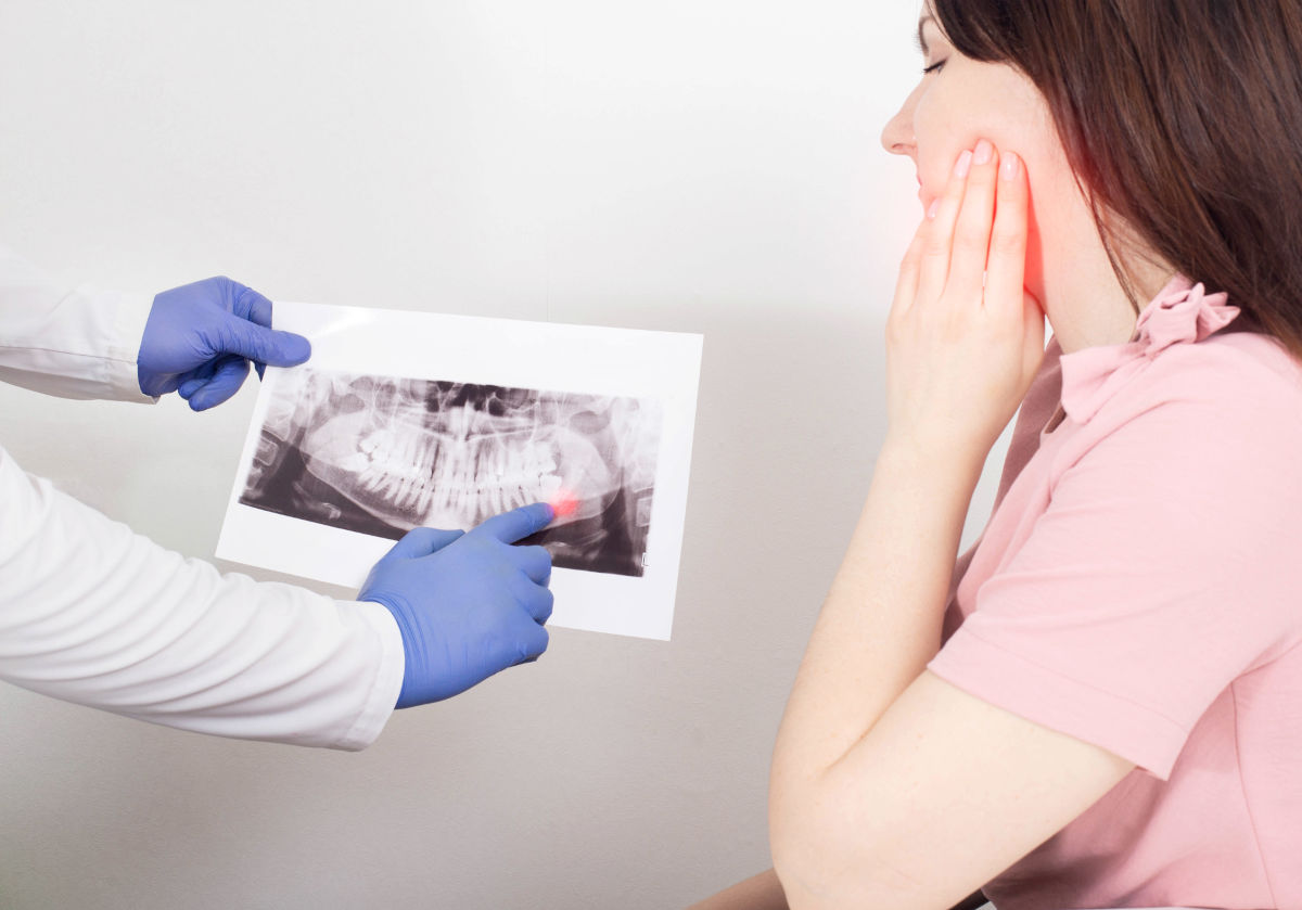 Dentist pointing to an infection at a tooth root on a dental X-ray